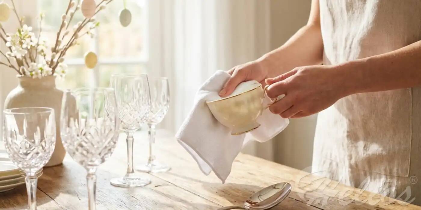 Elegancka biała porcelana ze złotym rantem i lśniące kieliszki przygotowywane na wielkanocny stół metodą Deep Clean