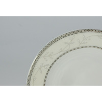 Zbliżenie na krawędź talerza z zestawu kawowego Ćmielów B601 Astra. Kremowa porcelana zdobiona delikatnym motywem roślinnym oraz geometrycznym, srebrnym wzorem.