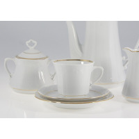 Elegancki garnitur do kawy Chodzież Kamelia B014. Biała porcelana ze złotym zdobieniem, widoczna filiżanka na spodku, cukiernica z pokrywką oraz dzbanek.