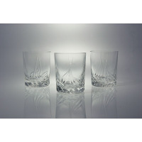Trzy szklanki 180 ml Monica marki Zawiercie z przezroczystego szkła kryształowego, ozdobione eleganckim, szlifowanym wzorem roślinnym na tle jasnej powierzchni.