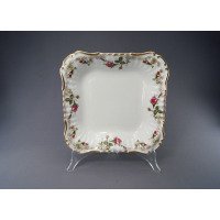 Kwadratowa salaterka Chodzież Iwona B013 o średnicy 28 cm. Biała porcelana z delikatnym reliefem, zdobiona motywem róż i złotym wykończeniem brzegów na stojaku.
