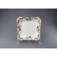 Kwadratowa salaterka Chodzież Iwona B013 o wymiarach 24 cm z białej porcelany, ozdobiona motywem róż i złoconymi brzegami, wyeksponowana na przezroczystym