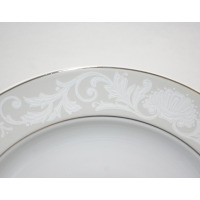 Zbliżenie na brzeg porcelanowego talerza z zestawu kawowego Chodzież E373 YVONNE. Jasnoszary pas zdobi subtelny, biały ornament roślinny z wykończeniem w