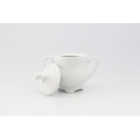 Biała cukiernica 0,40 l z kolekcji Rococo marki Ćmielów. Eleganckie naczynie z porcelany o bogatym, tłoczonym zdobieniu, widoczne z otwartą pokrywką obok.
