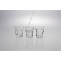 Trzy szklane kieliszki do wódki ARAS marki LAV o pojemności 45 ml. Środkowy kieliszek jest napełniany płynem, a prawy jest już pełny. Minimalistyczny design na