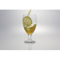 Szklanka na nodze EMPIRE marki LAV wypełniona mrożoną herbatą z lodem i plastrem cytryny. Eleganckie naczynie o pojemności 590 ml w trakcie napełniania napojem.