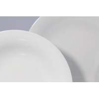 Zbliżenie na dwa białe talerze z porcelany Lubiana Tiago. Naczynia wyróżniają się subtelną, prążkowaną teksturą na brzegach, tworzącą elegancki zestaw obiadowy.