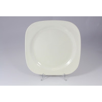 Kwadratowy talerz płytki RAK Porcelain o średnicy 31 cm z serii SKA. Minimalistyczne białe naczynie o zaokrąglonych rogach, wyeksponowane na przezroczystym