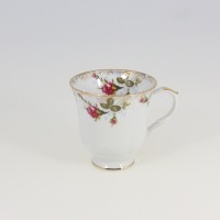 Filiżanka Chodzież 0,40 l z serii Iwona Złota róża. Biała porcelana ozdobiona motywem róż i delikatnym złoceniem na krawędziach. Widok z profilu na tle.