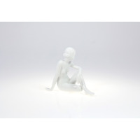 Biała porcelanowa figurka Zamyślona 0001 marki Ćmielów. Subtelna rzeźba przedstawia nagą kobietę siedzącą w zamyśleniu, wykonaną z gładkiej, błyszczącej