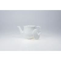 Biały porcelanowy czajnik 0,55 l z serii ROCOCO marki Ćmielów. Naczynie o klasycznym, zdobionym reliefami kształcie, z odłożoną obok pokrywką na jasnym tle.