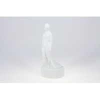Biała porcelanowa figurka Kobieta Upadła z manufaktury Ćmielów. Smukła postać kobieca w minimalistycznym stylu, ukazana w ujęciu z profilu na owalnej podstawie.