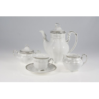 Porcelanowy garnitur do kawy Ćmielów E361 Bolero: biały dzbanek, cukiernica, mlecznik oraz filiżanka ze spodkiem, zdobione subtelnym, srebrnym ornamentem.