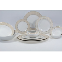 Serwis obiadowy Chodzież G620 YVONNE dla 12 osób. Zestaw 44 części z białej porcelany ze zdobionym beżowo-złotym wzorem na brzegach, wyeksponowany w aranżacji.