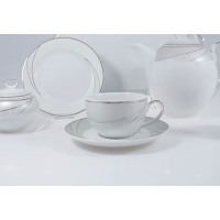 Elegancki zestaw kawowy Chodzież E615 YVONNE: biała porcelana ze srebrnym zdobieniem, filiżanka na spodku, cukiernica, talerzyk i dzbanek na jasnym tle.