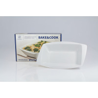 Białe porcelanowe naczynie do zapiekania Lubiana Rumba 330x202x61mm ustawione przed opakowaniem Bake&Cook z grafiką gotowej potrawy. Widok z przodu.