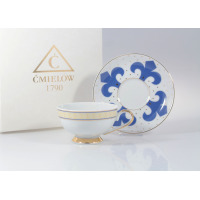 Filiżanka do herbaty 0,22 l ze spodkiem Ćmielów G340 ASTRA z białej porcelany. Zdobiona niebieskim wzorem fleur-de-lis, złotymi akcentami i logo Ćmielów 1790.