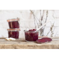 Trzy szklane słoiki Weck Sturz 200 ml wypełnione ciemnoczerwoną konfiturą z buraków, ustawione na drewnianym blacie obok plasterków świeżego warzywa i imbiru.