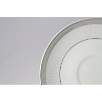 Zbliżenie na biały spodek z serii E685 YVONNE marki Ćmielów. Porcelanowy talerzyk zdobi elegancki, szary wzór grecki na obrzeżu oraz subtelne, pionowe prążki.