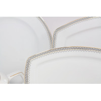 Zbliżenie na białą porcelanę Ćmielów z serwisu obiadowego 8051 Pułaski. Widoczny elegancki złoty wzór greckiej drogi na krawędziach kwadratowych talerzy.