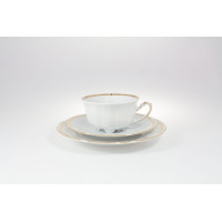 Biała filiżanka ze spodkiem z zestawu do herbaty Ćmielów E337 Bolero. Porcelana z delikatnym złotym zdobieniem na krawędziach, widok z boku na tle białego