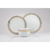 Zestaw herbaciany Ćmielów E551 Bolero Princess: biała porcelanowa filiżanka na nóżkach, spodek i talerz deserowy z eleganckim złotym i srebrnym zdobieniem.