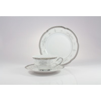 Zestaw herbaciany Ćmielów E361 Bolero Vera: biała porcelana ze srebrnym zdobieniem, filiżanka na spodku oraz talerz deserowy ustawiony pionowo w tle.