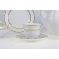 Elegancka filiżanka ze spodkiem z zestawu kawowego Ćmielów E363 Bolero Vienna. Biała porcelana ze złotym zdobieniem i kremowym wzorem, widoczna na tle serwisu.