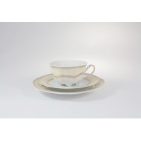 Zestaw herbaciany Ćmielów E363 Bolero: filiżanka na spodku ustawiona na talerzyku deserowym. Elegancka porcelana w odcieniach kremu ze złotym, ażurowym