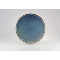 Talerz płytki Verlo Deep Blue o średnicy 28,5 cm na przezroczystym stojaku. Ceramiczne naczynie w odcieniach głębokiego błękitu z charakterystyczną kropkowaną