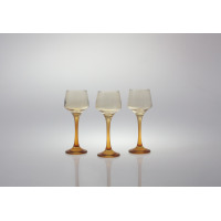 Trzy kieliszki do likieru 75 ml Sunset Miodowy marki Glasmark ustawione w rzędzie na białym tle. Szklane naczynia o smukłych, miodowych nóżkach i