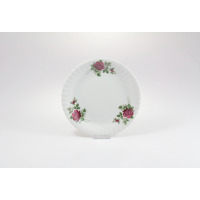 Talerz deserowy Chodzież Iwona o średnicy 19 cm z białej porcelany. Dekorację stanowi motyw bordowej róży z zielonymi liśćmi, umieszczony na karbowanym brzegu