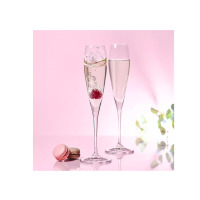 Dwa eleganckie kieliszki do szampana Perla od Krosno Glass na różowym tle. W jednym kieliszku zanurza się malina, tworząc efektowne rozbryzgi. Obok leżą