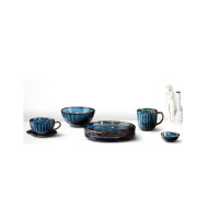 Zestaw ceramicznych naczyń Verlo Deep Blue w odcieniach głębokiego błękitu z brązowymi rantami. Widoczna miska 18 cm, filiżanki, talerze oraz mała salaterka w