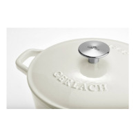 Kremowa brytfanna żeliwna Gerlach Natur Iron o pojemności 5,5 l. Zbliżenie na pokrywkę z wytłoczonym napisem GERLACH oraz metalowy uchwyt z logo marki.