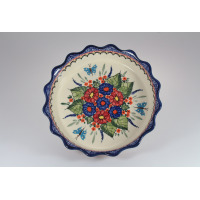 Ceramiczna salaterka Bolesławiec 149AR o średnicy 24,8 cm z falistym brzegiem. Kremowe wnętrze zdobi ręcznie malowany wzór w kwiaty i niebieskie motyle.
