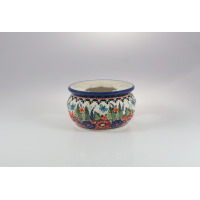 Ceramiczny podgrzewacz Bolesławiec 149AR o średnicy 13,9 cm. Naczynie zdobi ręcznie malowany wzór w kwiaty i motyle na kremowym tle z niebieskim rantem.