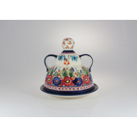 Ceramiczna baba do sera 19,2 cm GU-847 od Bolesławiec. Naczynie z pokrywką zdobione ręcznie malowanym motywem kwiatów i motyli w żywych kolorach na jasnym tle.