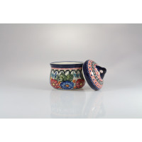 Ceramiczny pojemnik Bolesławiec 0,20 l GU-1600 z ręcznie malowanym motywem kwiatowym i motylami. Obok stoi dopasowana pokrywka z geometrycznym wzorem.