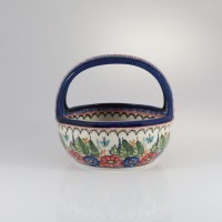 Ceramiczny koszyk Bolesławiec 149AR o średnicy 17,5 cm. Naczynie z uchwytem zdobi ręcznie malowany wzór w kwiaty, liście i motyle na kremowym tle z niebieskim