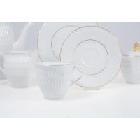 Zestaw do kawy Ćmielów 3604 Sofia ze złoceniami. Biała porcelana z tłoczonym wzorem, filiżanka na pierwszym planie, w tle spodek, dzbanek i cukiernica.