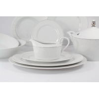 Zestaw obiadowy dla 6 osób Ćmielów G856 Jenny. Biała porcelana z subtelnym, kropkowanym wzorem na brzegach. Na pierwszym planie sosjerka na talerzyku, w tle