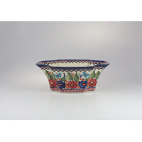 Ceramiczna salaterka Bolesławiec 149AR o wymiarach 27,5 x 19 cm. Naczynie o falistym kształcie zdobi ręcznie malowany wzór w czerwone i niebieskie kwiaty oraz
