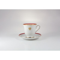 Biała porcelanowa filiżanka 0,25 l ze spodkiem Ćmielów G516 ASTRA. Naczynie zdobi złoty polski orzeł, czerwony pasek oraz eleganckie złocenia na krawędziach.
