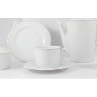 Zestaw do kawy dla 6 osób Ćmielów G856 Jenny z białej porcelany z delikatnym, szarym kropkowanym wzorem. Widok na filiżankę ze spodkiem, dzbanek oraz talerzyk.