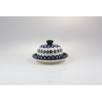 Ceramiczna maselnica Bolesławiec GU-742 z pokrywką, zdobiona tradycyjnym wzorem w niebieskie kwiaty i kółka na kremowym tle, widok z przodu na białym tle.
