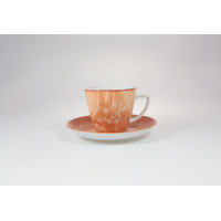 Pomarańczowa filiżanka 350 ml ze spodkiem marki Lubiana. Naczynie zdobi subtelny, biały wzór roślinny. Elegancka porcelana w ciepłym odcieniu na białym tle.