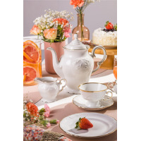 Elegancki garnitur do kawy Chodzież Fryderyka IVORY Złota Linia. Biała porcelana z subtelnym tłoczeniem i złotym zdobieniem na stole z kwiatami, owocami i