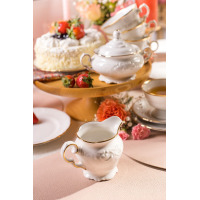 Elegancki mlecznik z kolekcji Fryderyka IVORY Złota Linia marki Chodzież. Kremowa porcelana z subtelnym tłoczeniem i złotym wykończeniem na tle zastawy kawowej.