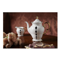 Biały porcelanowy imbryk Ćmielów G539 Alaska Dama Kier o pojemności 1,2 l ze złotym uchwytem i pionowym wzorem czarnych rombów, ustawiony na drewnianym stole